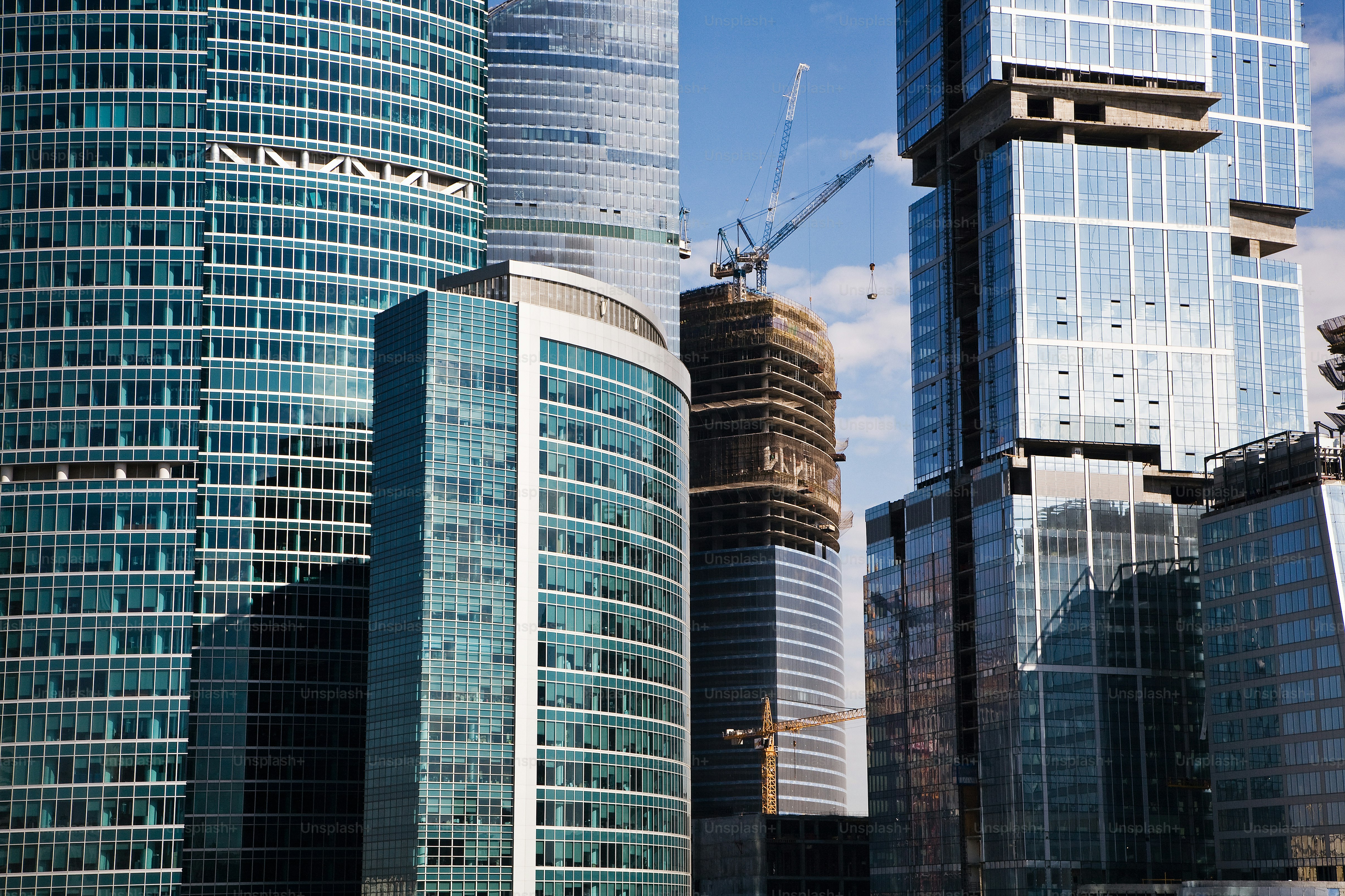 a group of tall buildings with cranes in the background