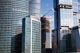 a group of tall buildings with cranes in the background