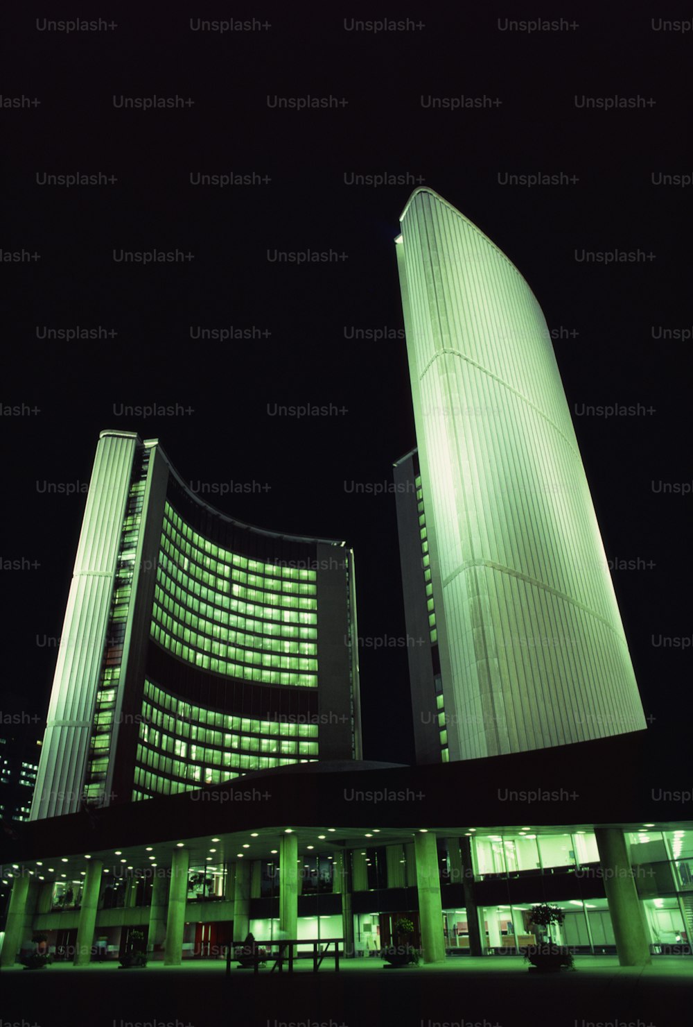 two tall buildings lit up at night in a city