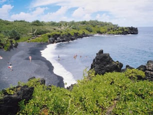 a group of people standing on top of a black sand beach