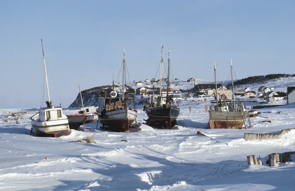 a group of boats that are sitting in the snow