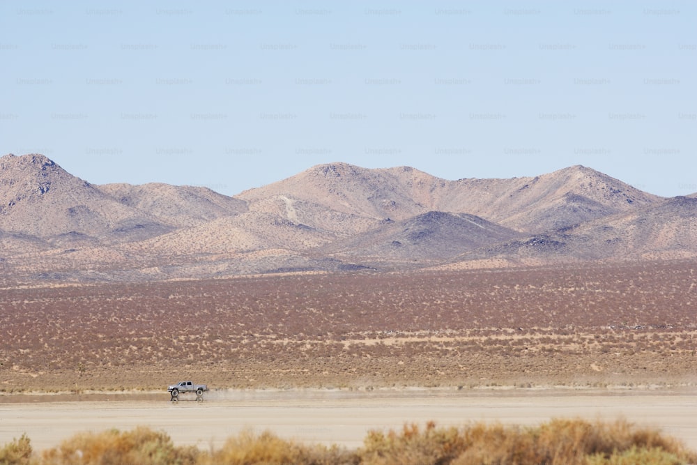 um caminhão dirigindo por um deserto com montanhas ao fundo