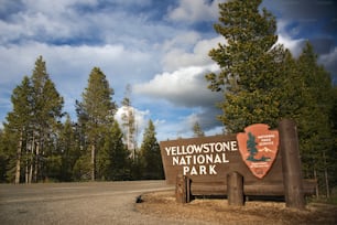Ein Schild für den Yellowstone-Nationalpark vor einigen Bäumen