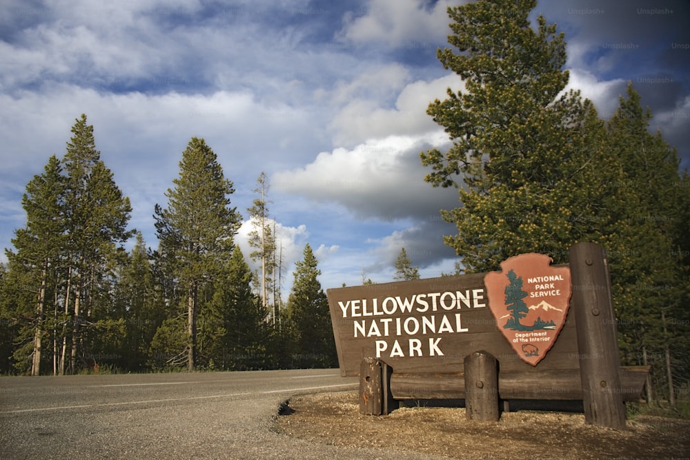 Uma placa para o Parque Nacional de Yellowstone na frente de algumas árvores