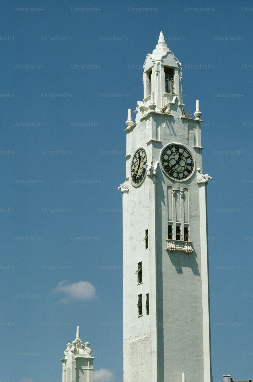 uma alta torre de relógio branca com um relógio em cada um de seus lados