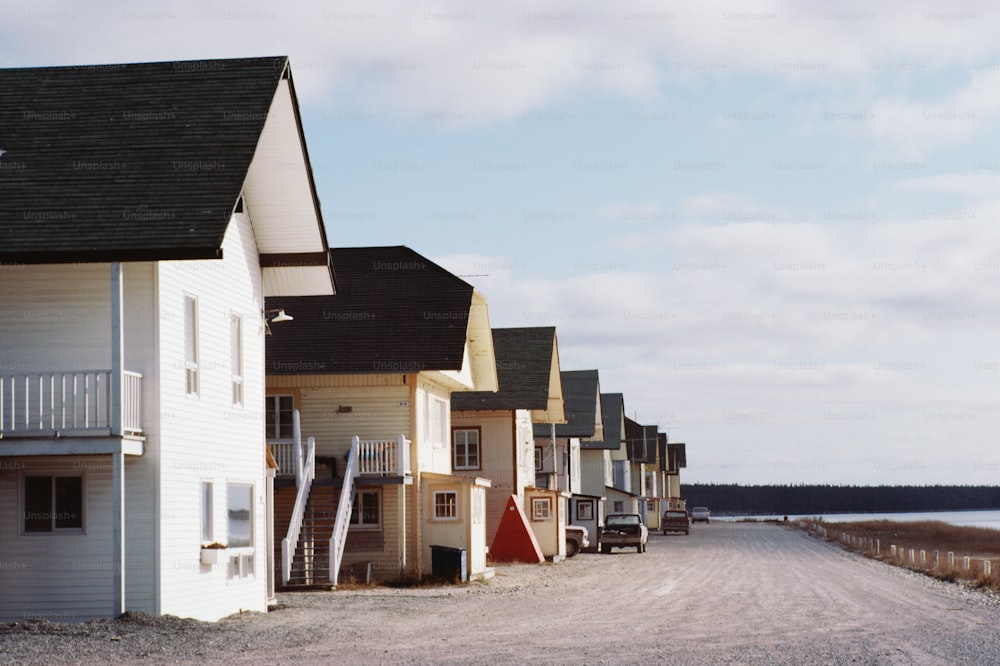 a row of houses on a dirt road next to a body of water