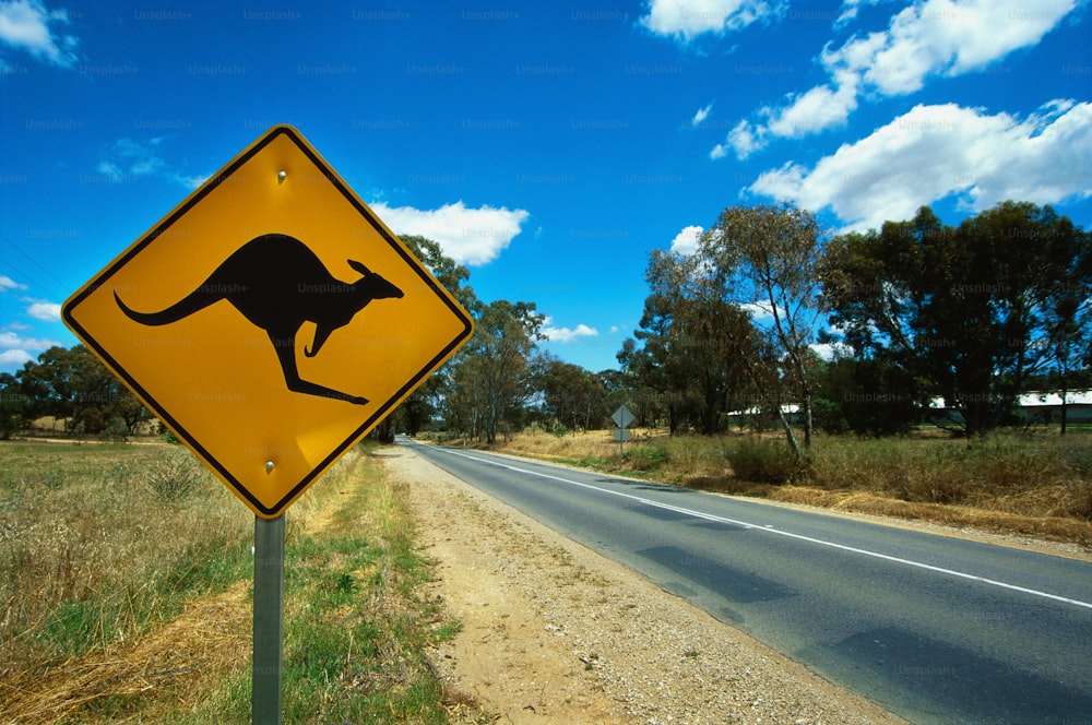 um sinal amarelo de travessia de canguru sentado na beira de uma estrada