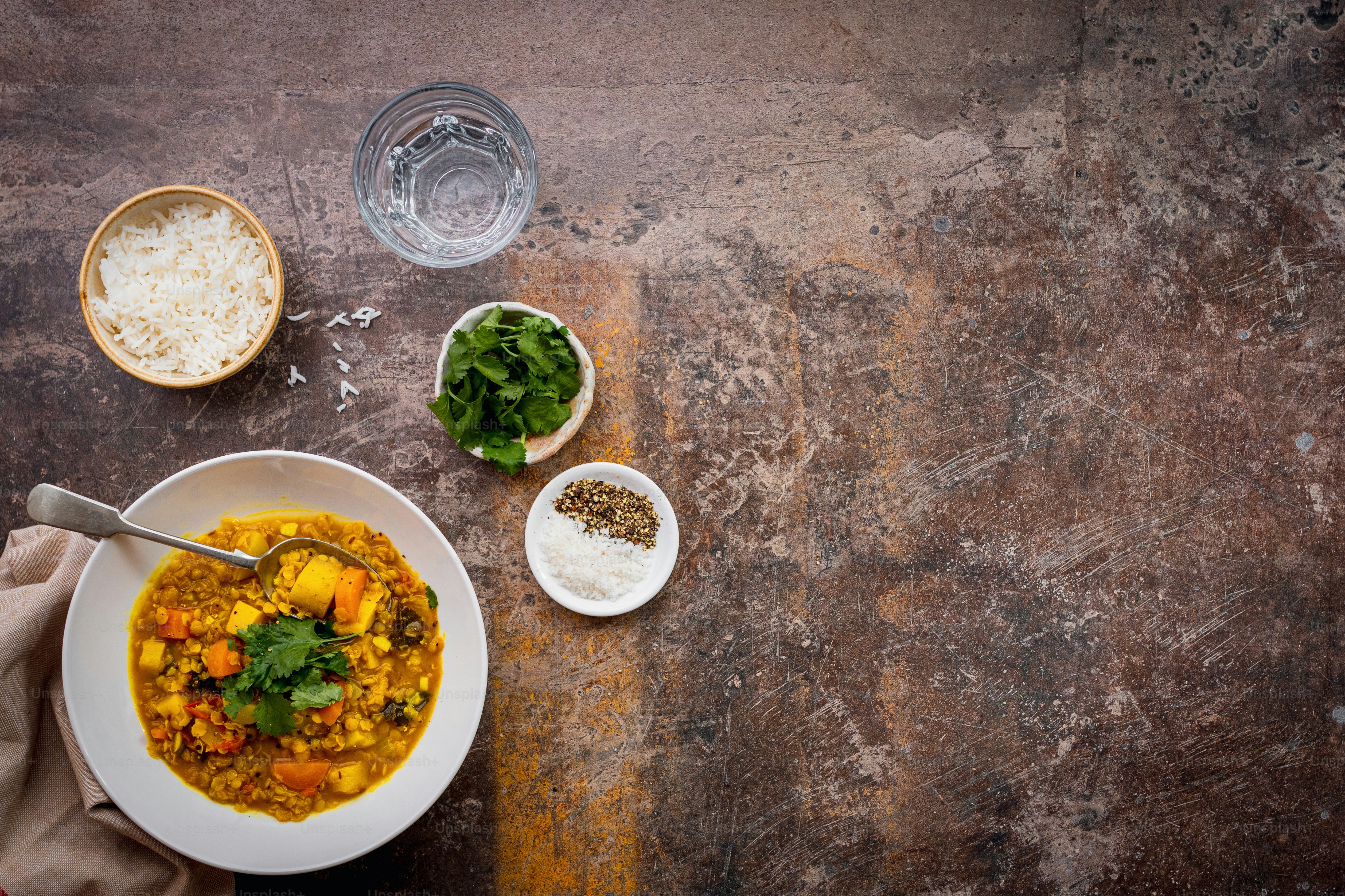 a bowl of soup with a spoon and two bowls of rice