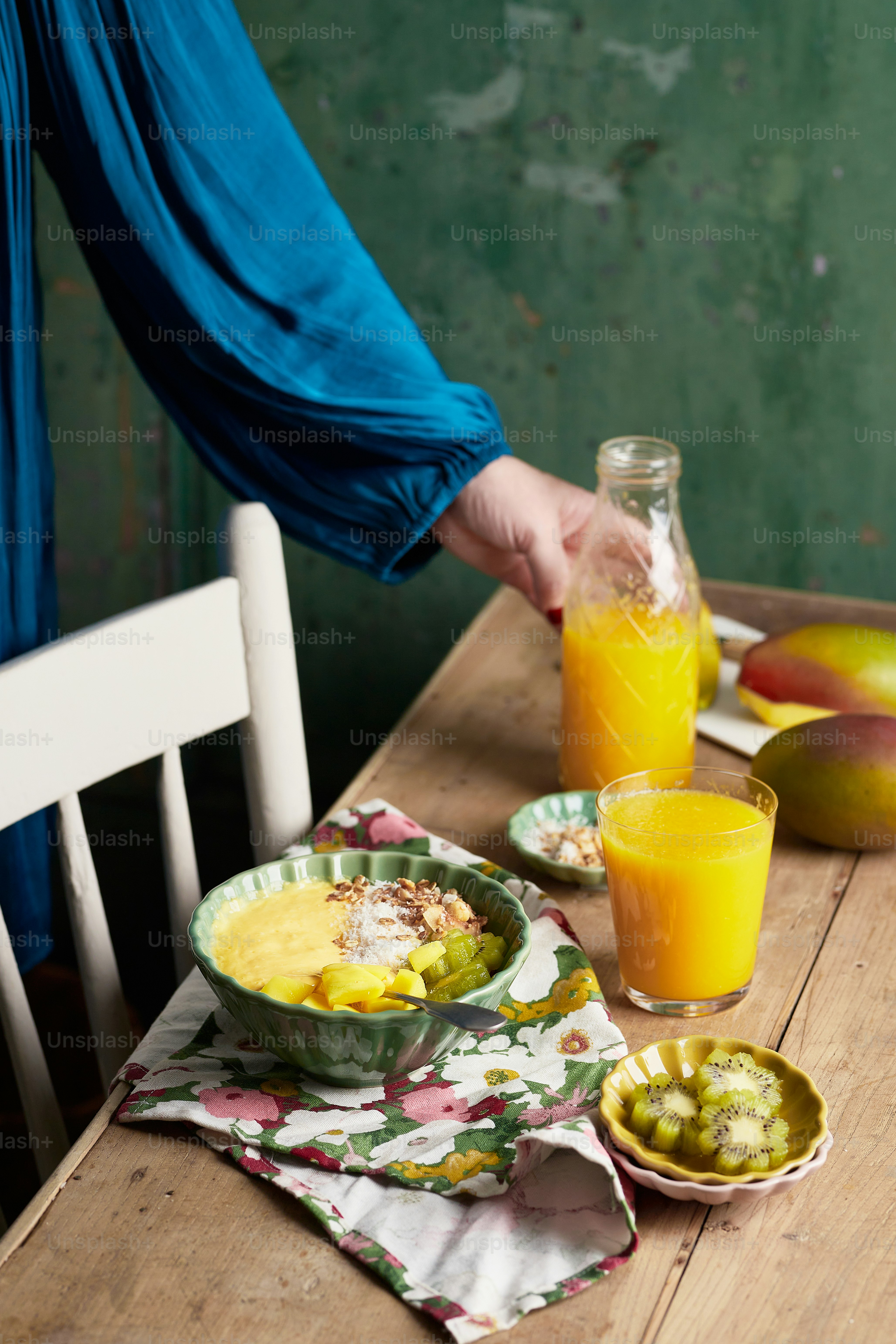 a person is holding a glass of orange juice