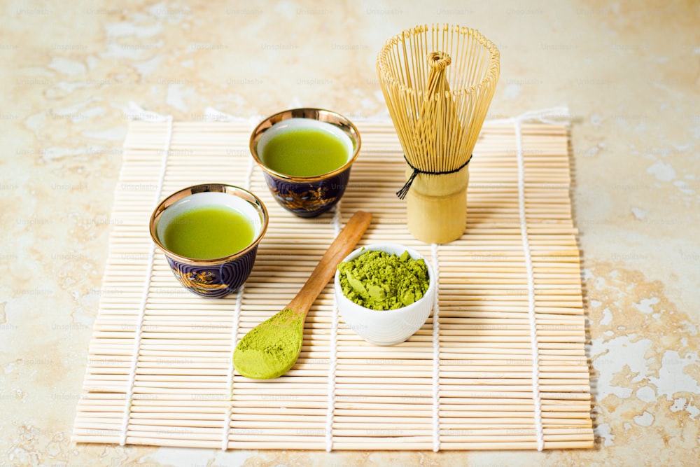 Drei Tassen grüner Tee auf einer Bambusmatte