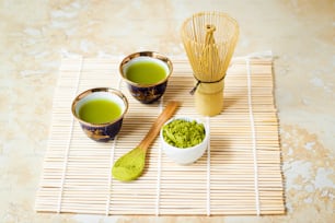 Trois tasses de thé vert sur un tapis de bambou