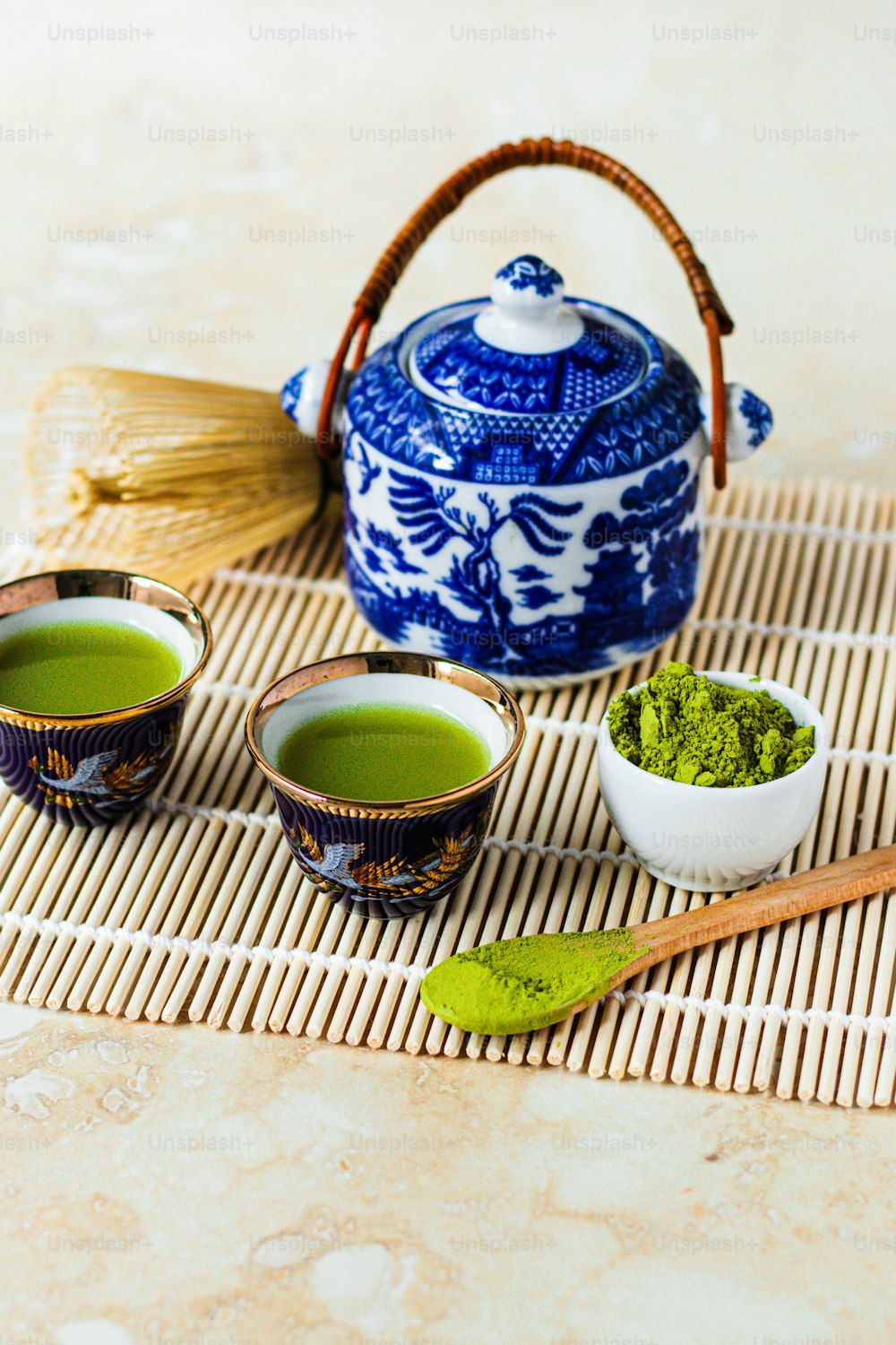 Due ciotole di tè verde accanto a una teiera