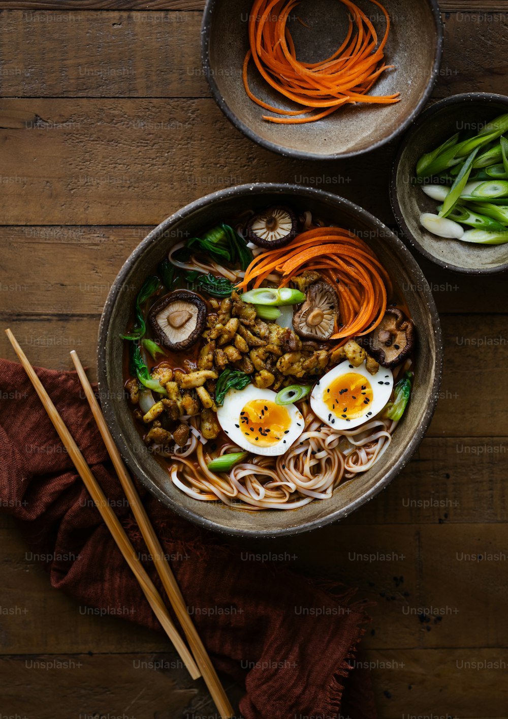 a bowl of noodles, carrots, mushrooms, and other vegetables