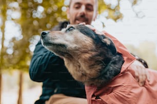 um homem segurando um cachorro usando uma capa de chuva