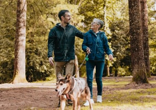 a man and woman walking a dog through a forest