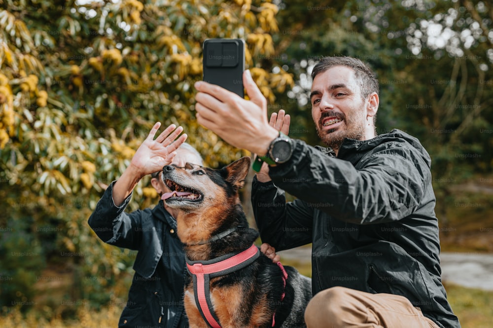 携帯電話で犬の写真を撮る男