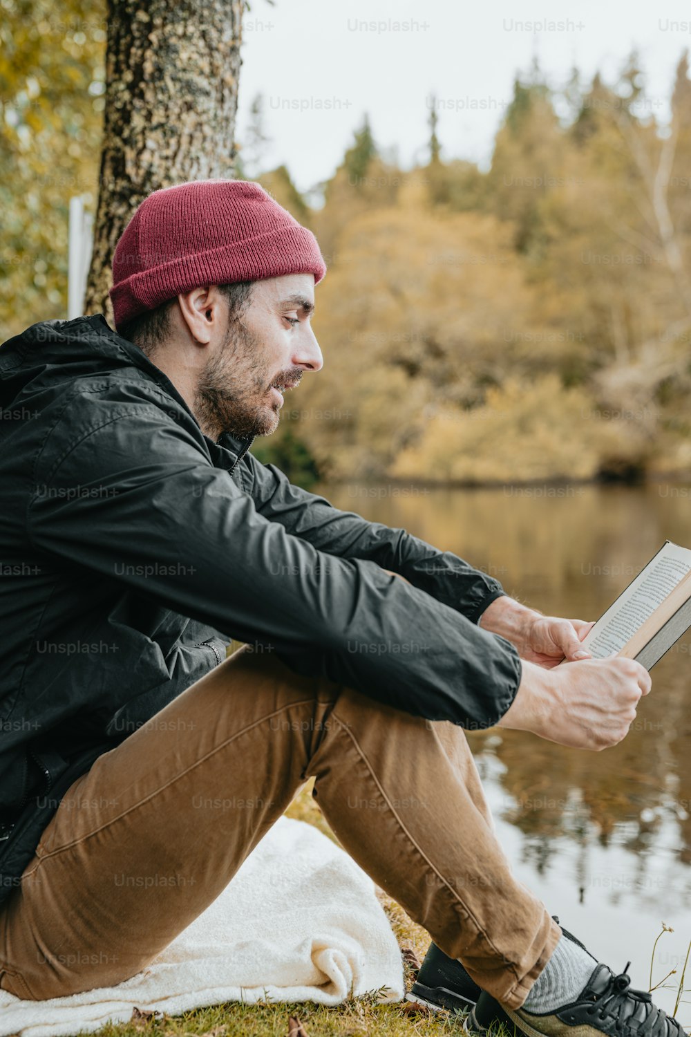 a man sitting by a lake reading a book