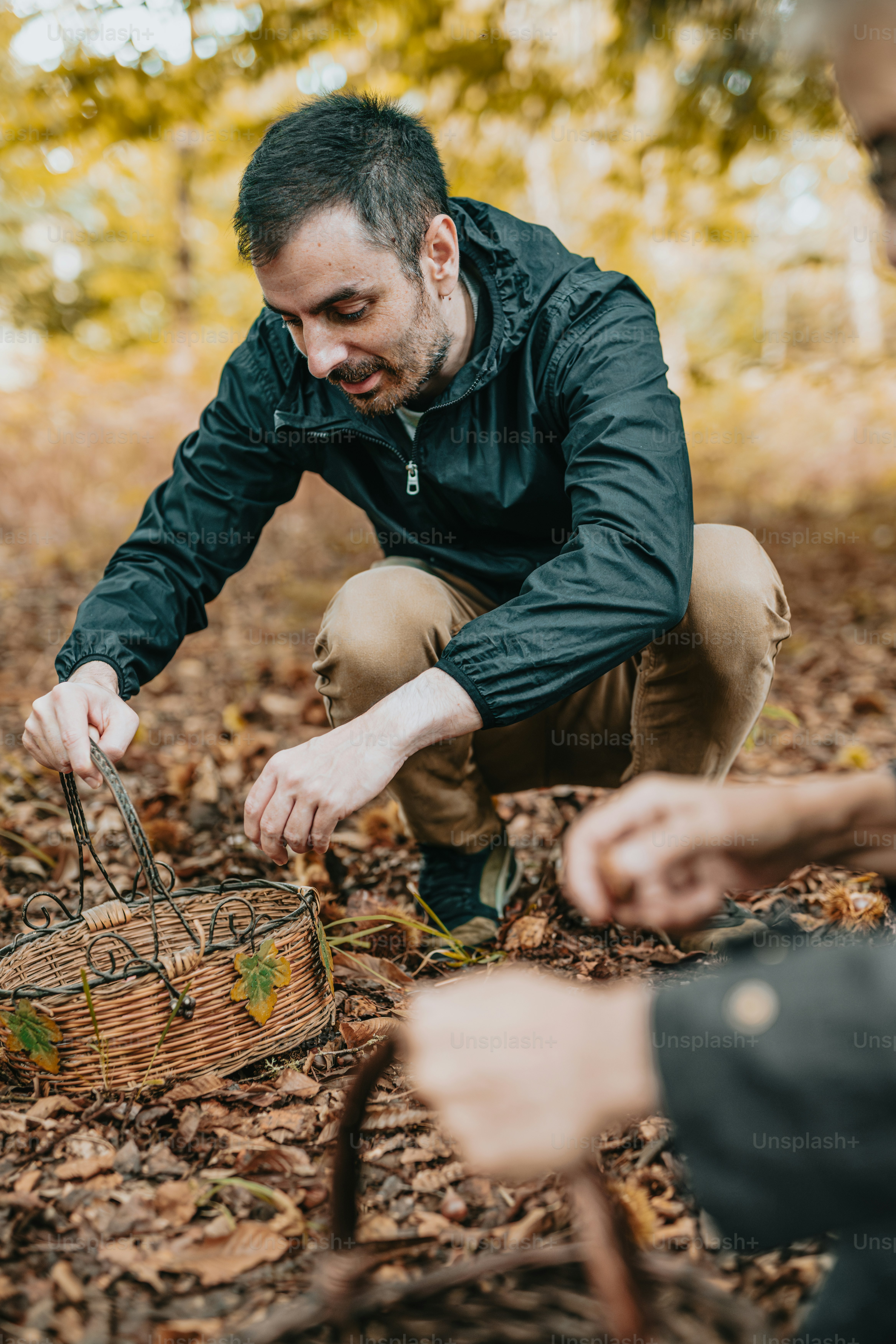 a man kneeling down next to a basket filled with leaves