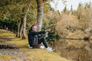 a man sitting next to a lake pointing at something