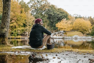 Un uomo seduto a terra vicino a un lago