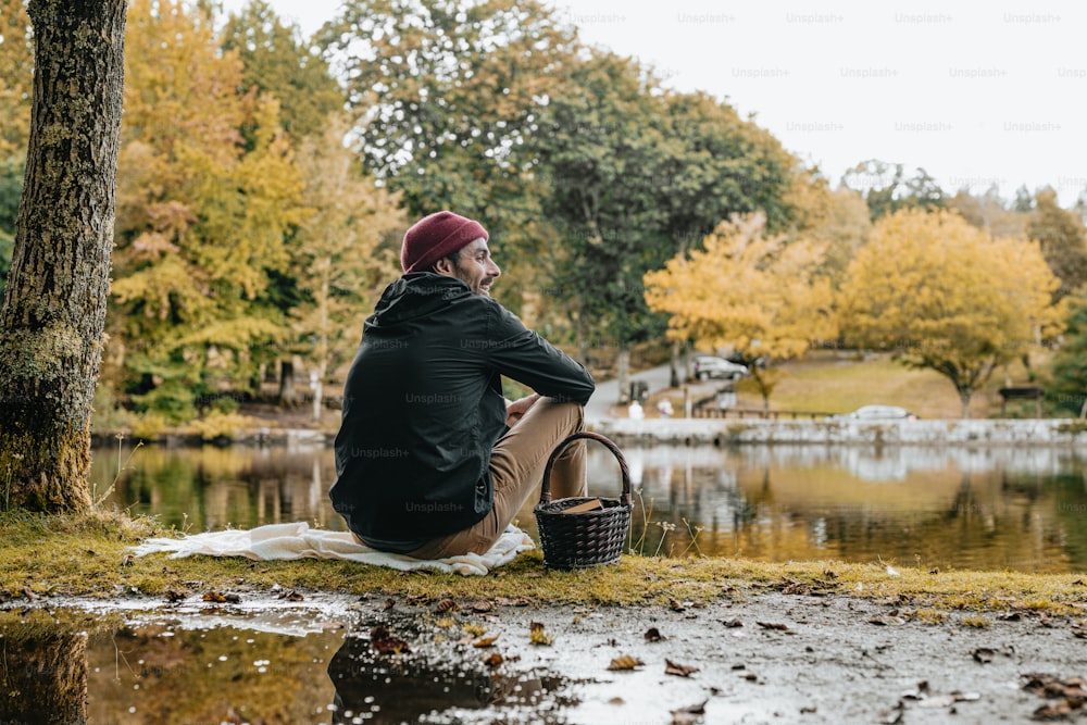 a man sitting on the ground next to a lake