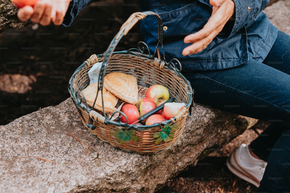 a person sitting on a rock with a basket of food