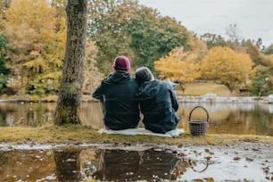 two people sitting on the ground next to a tree