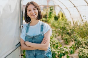 a woman standing in a greenhouse with her arms crossed