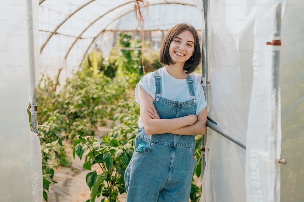 a woman standing in a greenhouse with her arms crossed