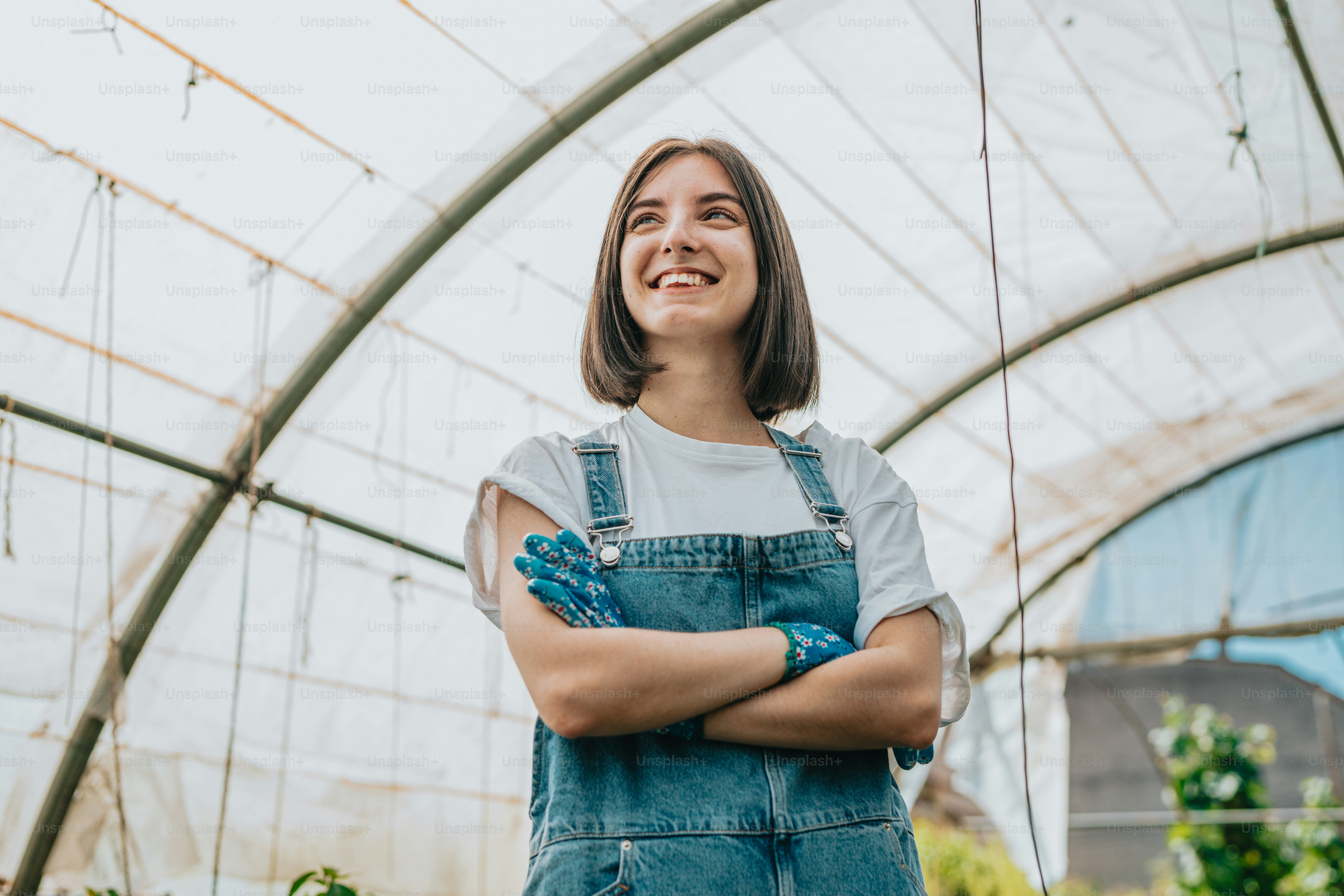 A woman standing in a greenhouse with her arms crossed photo – Farm ...
