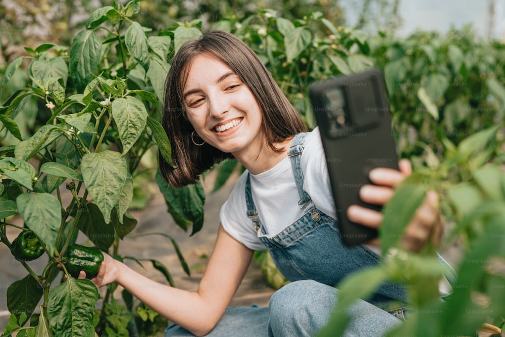 a woman kneeling in a field holding a tablet