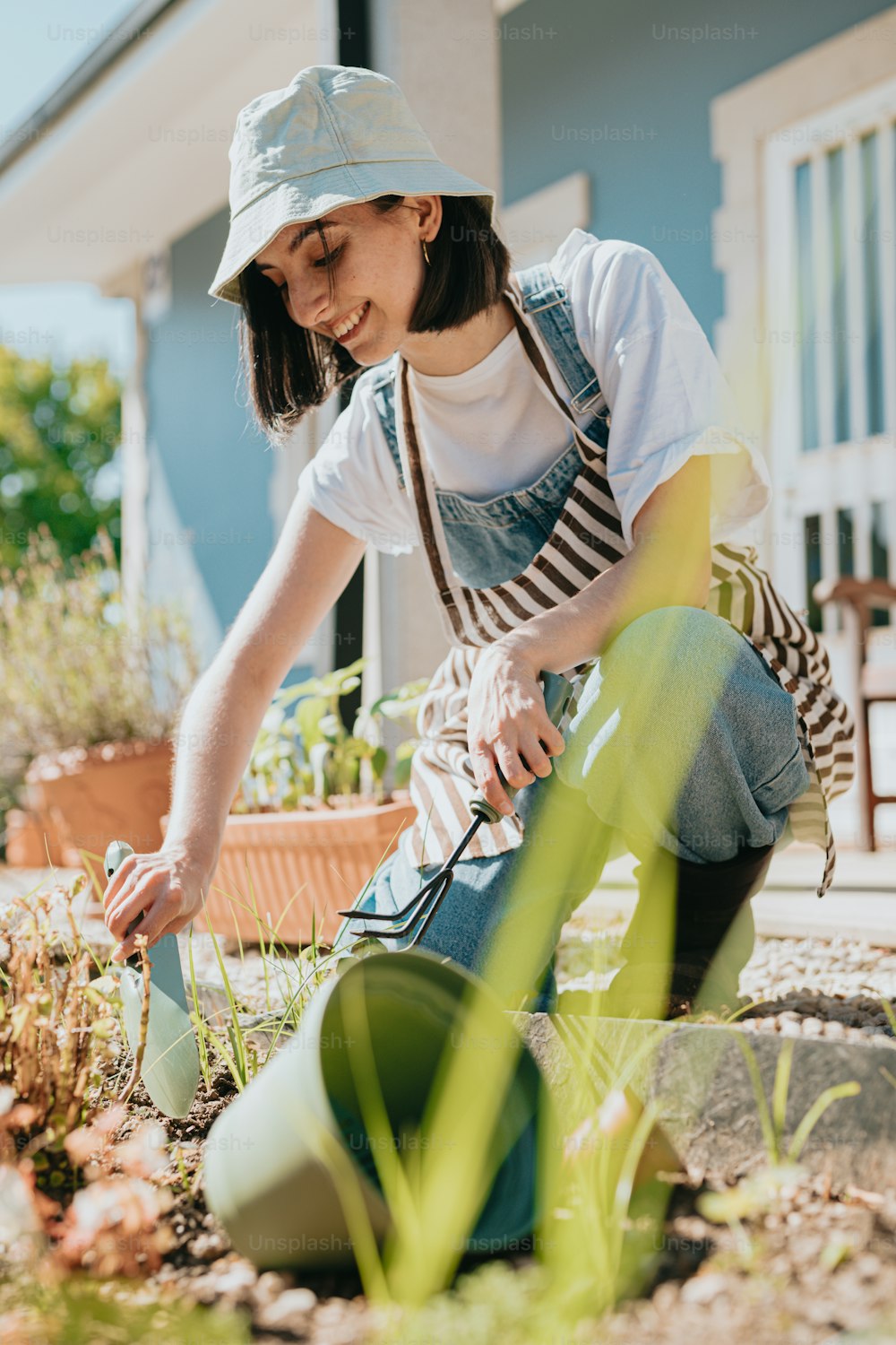 a woman kneeling down in the grass with a watering can