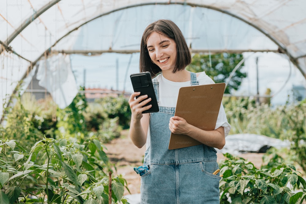 a woman standing in a greenhouse holding a tablet