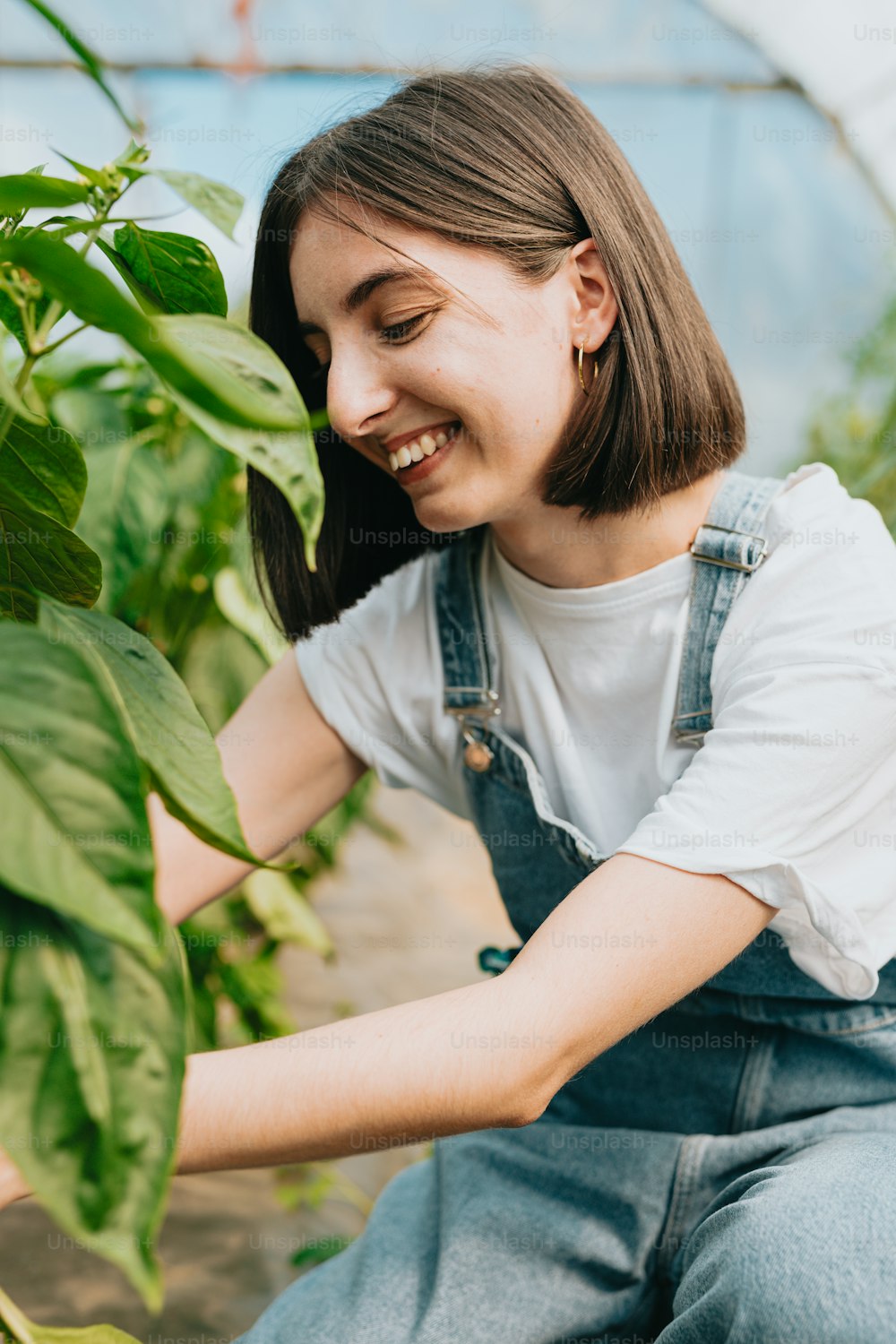 a woman is smiling as she holds a plant