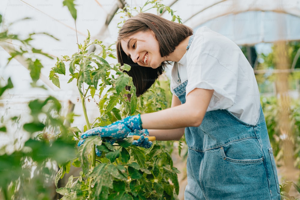 a woman in overalls working in a greenhouse