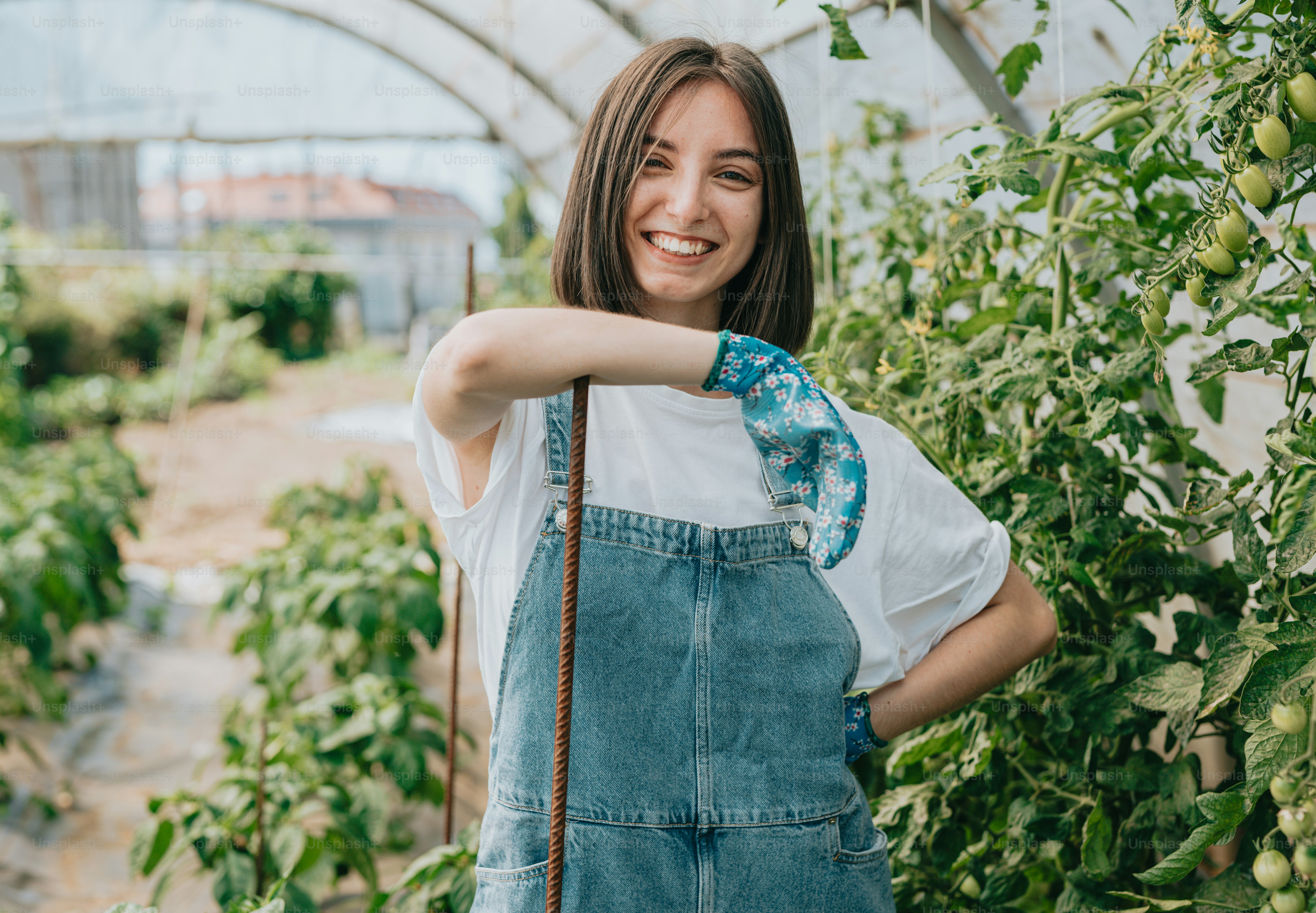 a woman standing in a greenhouse with her arms crossed