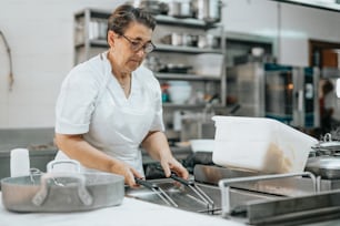 Una donna in camicia bianca sta cucinando in una cucina