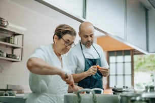 a man and woman in a kitchen preparing food