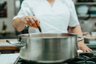 a person in a kitchen stirring something in a pot