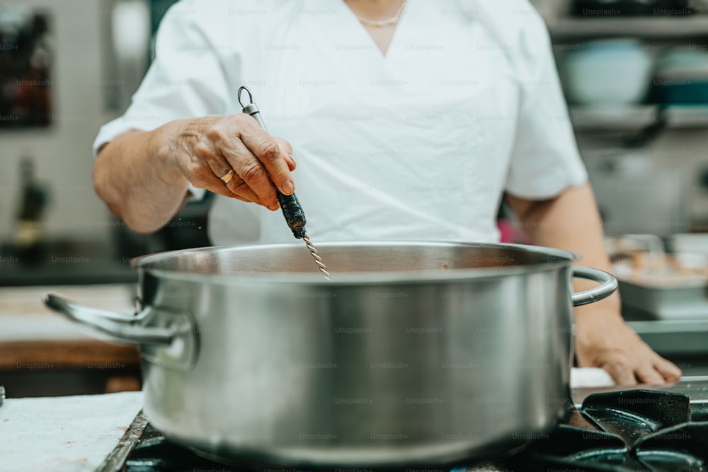 a person in a kitchen stirring something in a pot