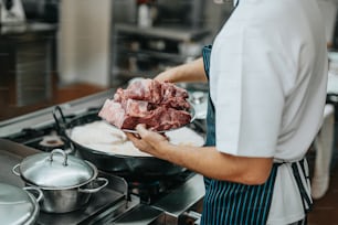 a man in a kitchen preparing food on top of a stove