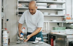 Un hombre en una cocina preparando comida en un plato