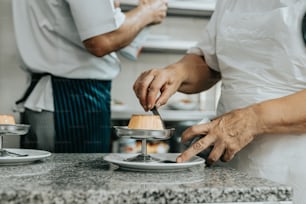 two people in a kitchen preparing food on a plate