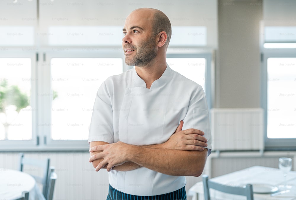 Un homme en uniforme de chef debout, les bras croisés