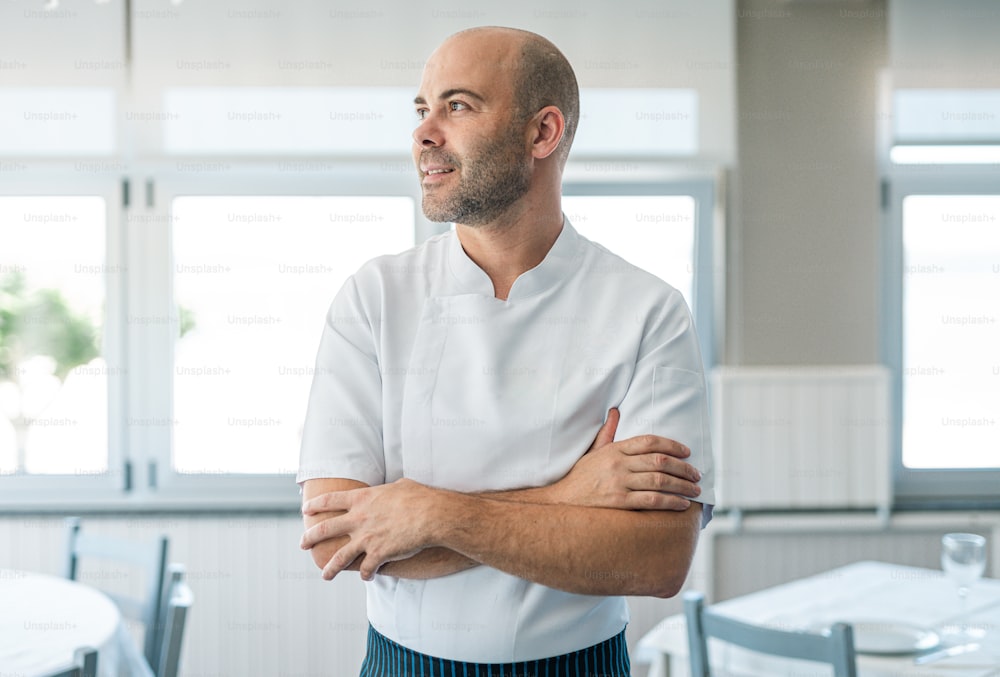 a man in a chef's uniform standing with his arms crossed