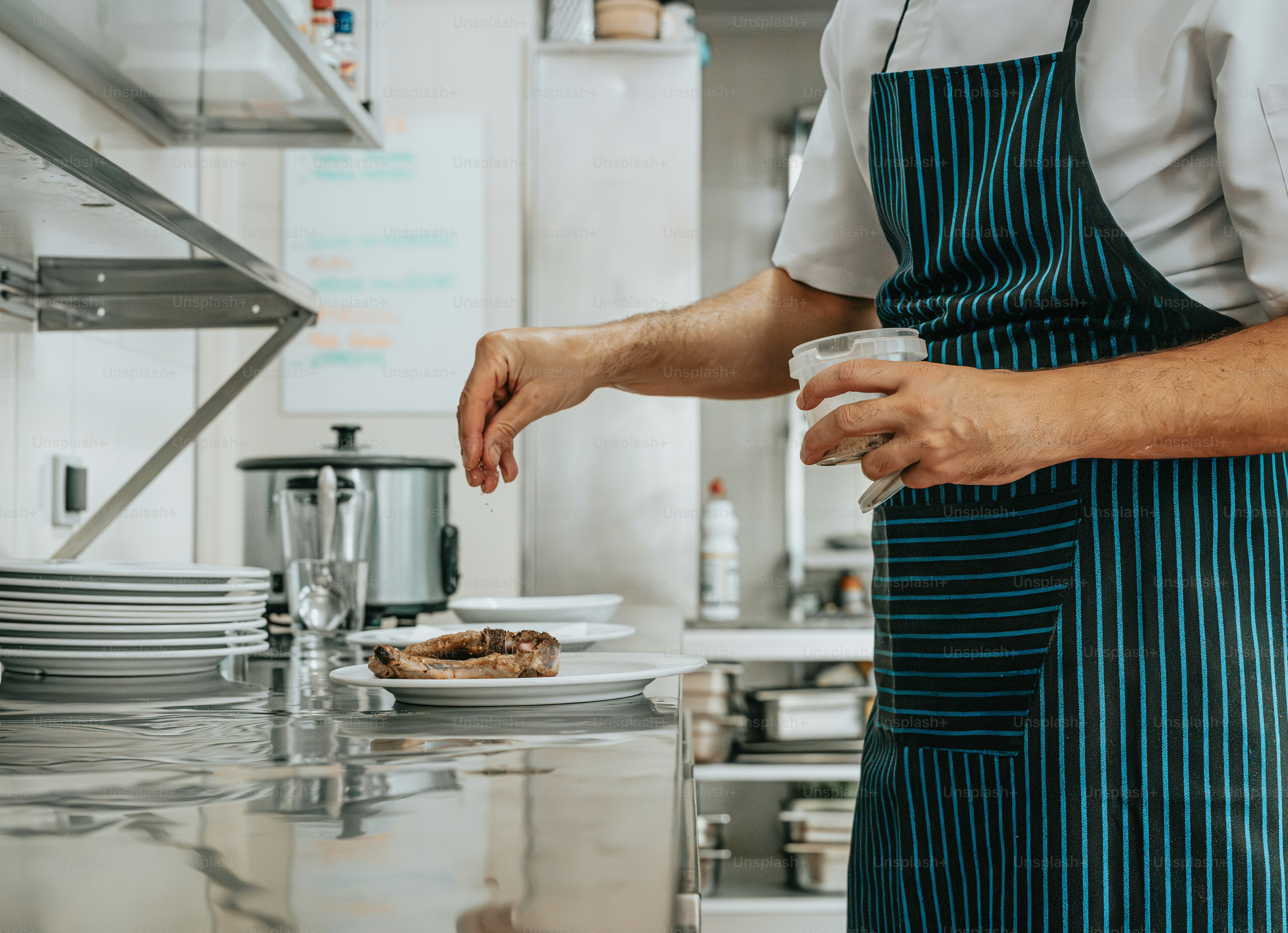a person in a kitchen preparing food on a plate