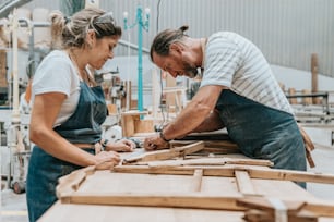 a man and a woman working on a piece of wood