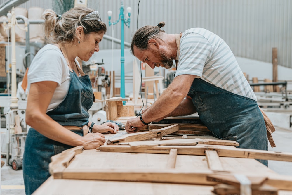 a man and a woman working on a piece of wood