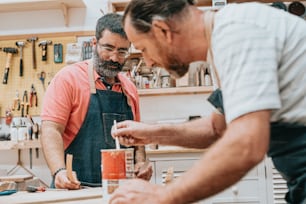 Dos hombres en un taller trabajando en un trozo de madera
