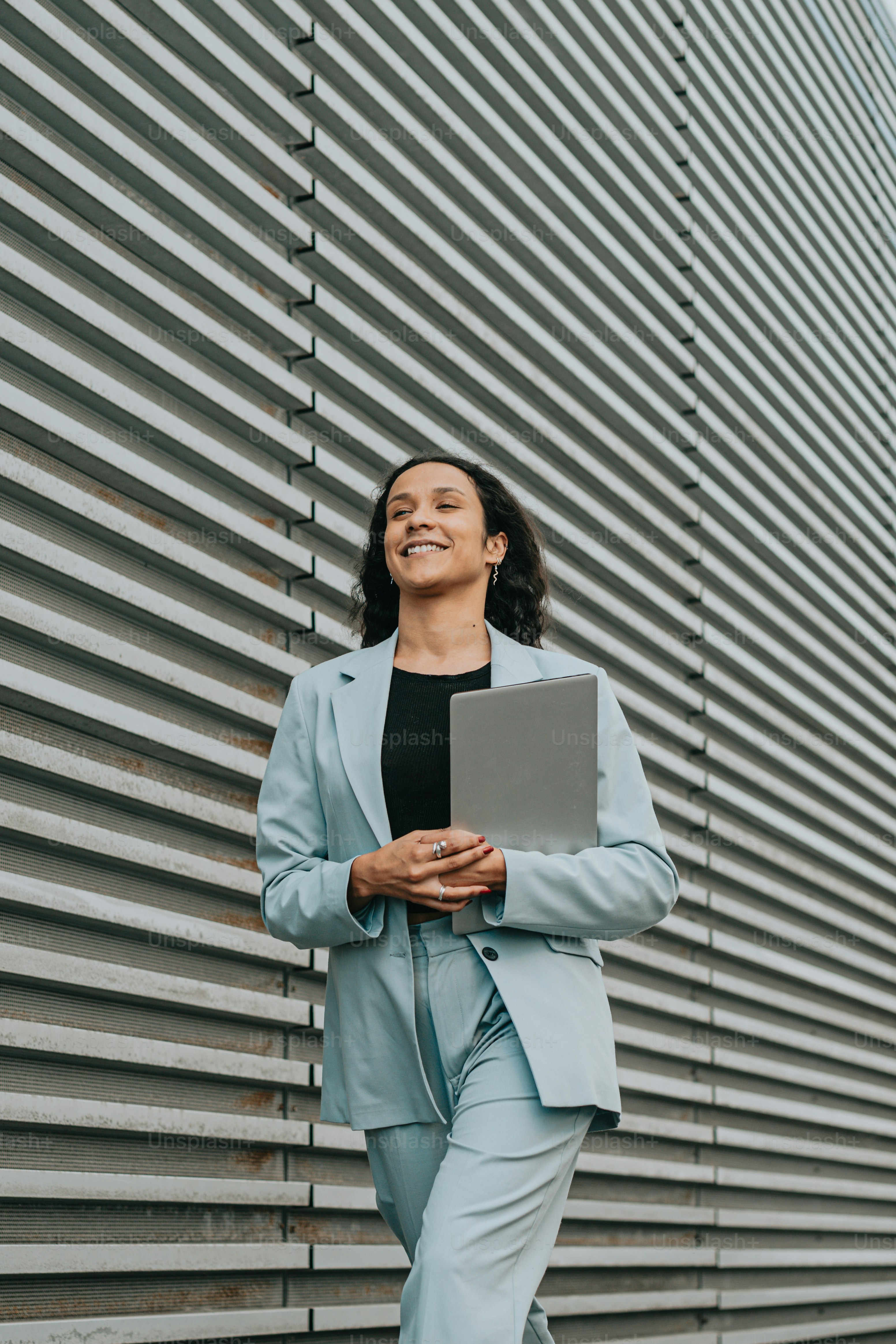 Una mujer parada frente a una pared con una computadora portátil